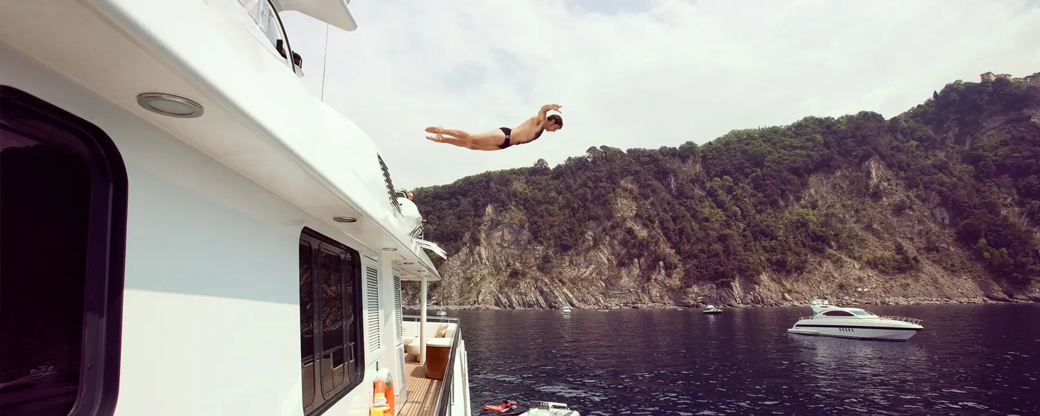 A man diving off of a boat into the water.